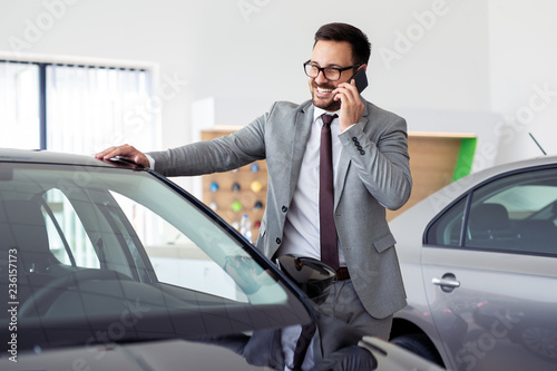 Businessman having a phone call at the car showroom