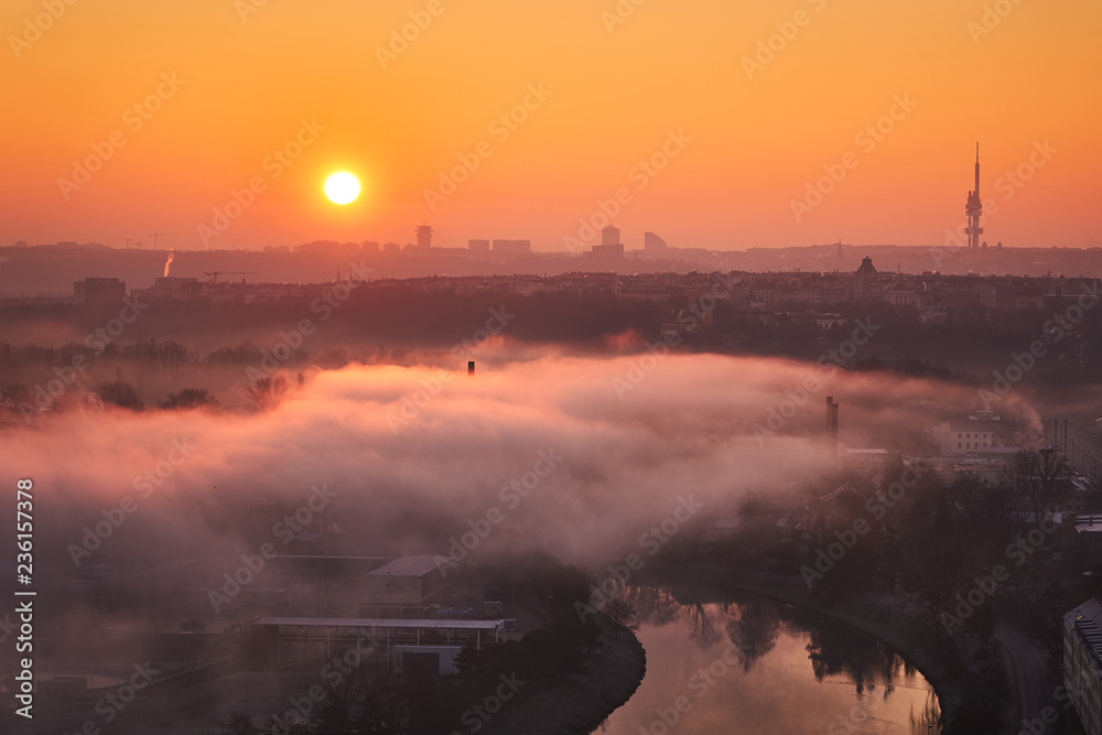 Morning Picture of cityscape of Prague, capitol of Czech Republic with landmark of vltava river and Television tower, second ugliest building in the world and clouds of smog taken in golden hour.