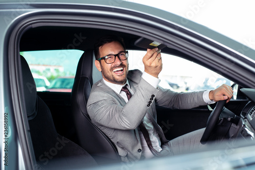 Handsome businessman is sitting in a new car in car dealership  © zorandim75