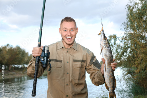 Man with rod and catch fishing at riverside. Recreational activity