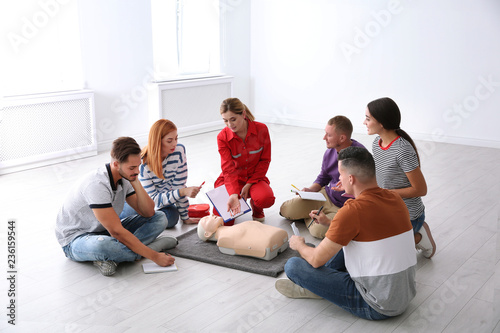 Group of people with instructor at first aid class indoors photo