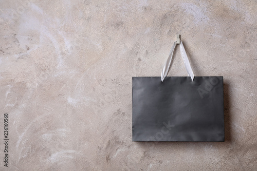 Paper shopping bag with handles hanging on color wall. Mock up for design