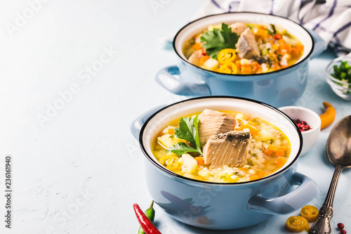 Fish soup with salmon, vegetables and couscous in blue pots. Selective focus, space for text.