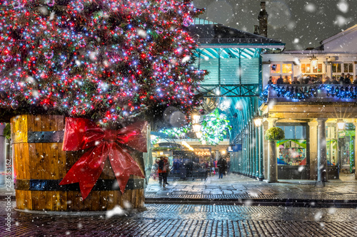 Weihnachtliches London im Bezirk Covent Garden mit Weihnachtsbaum und Schneefall bei Nacht