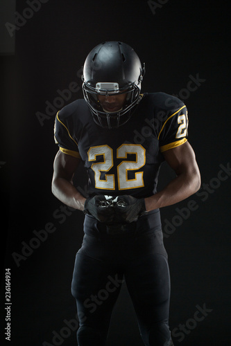 African American football player isolated on black.