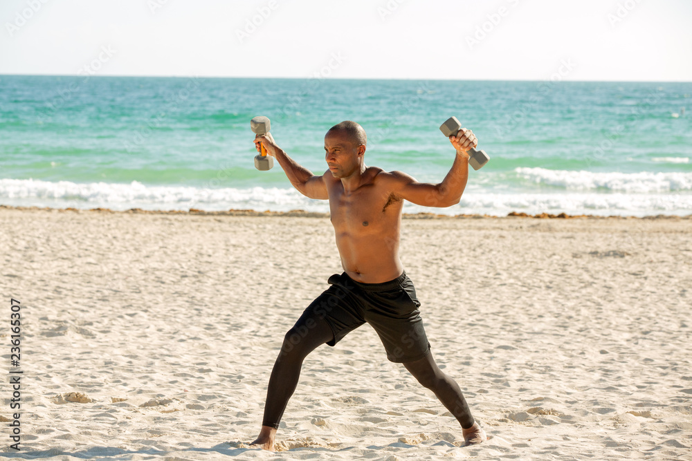 Man doing dumbbells on the beach Man doing dumbbells on the beach