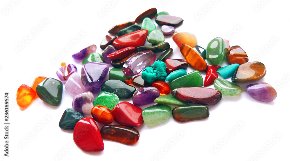 Spilling assorted natural bright coloured semi precious gemstones and gems on white background Spilling assorted natural bright coloured semi precious gemstones and gems on white background