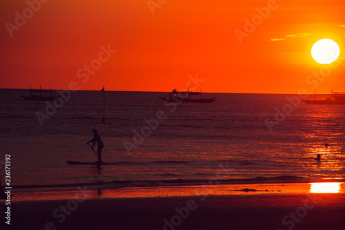 Dramatic orange sea sunset with boats. Summer time. Travel to Philippines. Luxury tropical vacation. Boracay paradise island. Seascape view. Tourism concept. Water transport. Paddle boarding © ra66