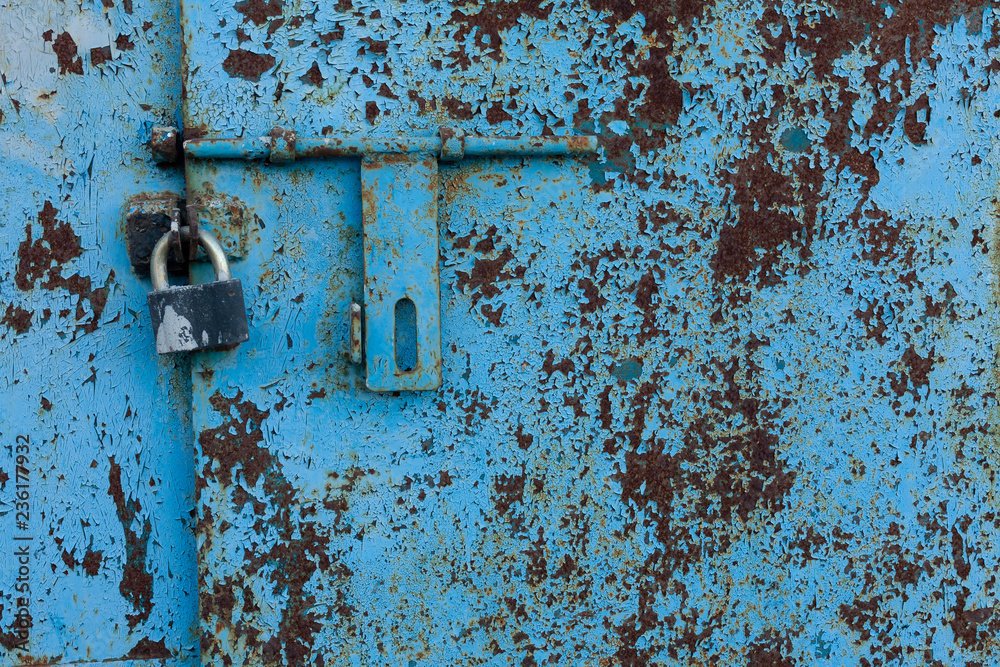 background fragment of an old rusty blue metal door with a padlock background fragment of an old rusty blue metal door with a padlock