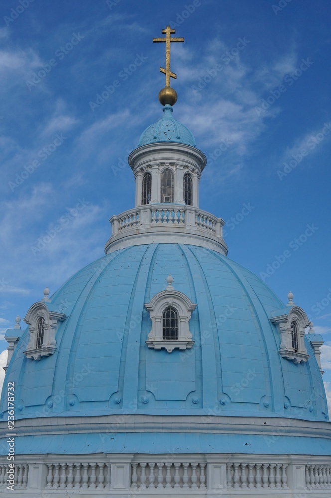 Beautiful great church, temple, cathedral view with gold cross in top in fir / pine park, forest with green colors and great blue sky. Spiritual white and gold, green and blue background.