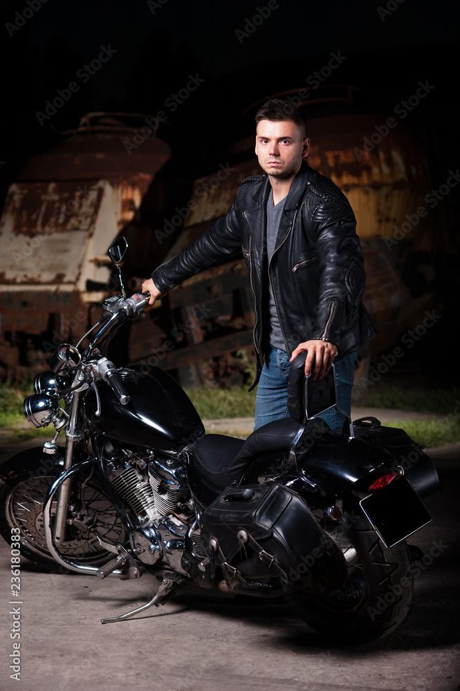Cute motorcyclist stands near his motorcycle  