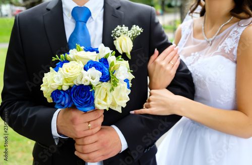 Bride and groom holding wedding bouquet with blue and yellow roses