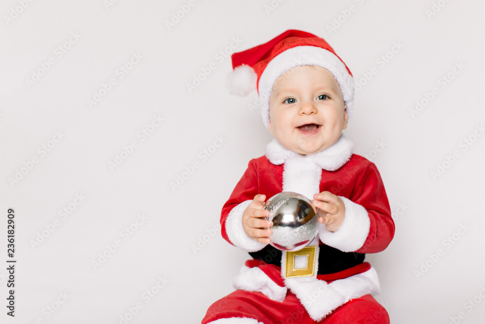 Beautiful little baby celebrates Christmas. New Year's holidays. Baby in a Christmas costume holding in her hands Christmas ball Beautiful little baby celebrates Christmas. New Year's holidays. Baby in a Christmas costume holding in her hands Christmas ball