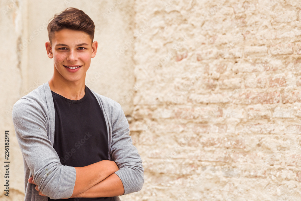 Portrait of the young man who is standing outdoor near the old house wall Portrait of the young man who is standing outdoor near the old house wall