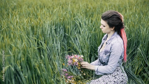 Slavic girl making a wreath. Flowers in the field. Girl in the field. Pagan Slavic rite. Pagan rite. Slavic girl making a wreath. Paganism. Girl making a wreath. Flowers in the field photo