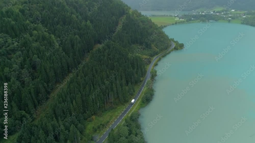 Aerial shot of white truck driving on road in the fjord valley Aerial shot of white truck driving on road in the fjord valley