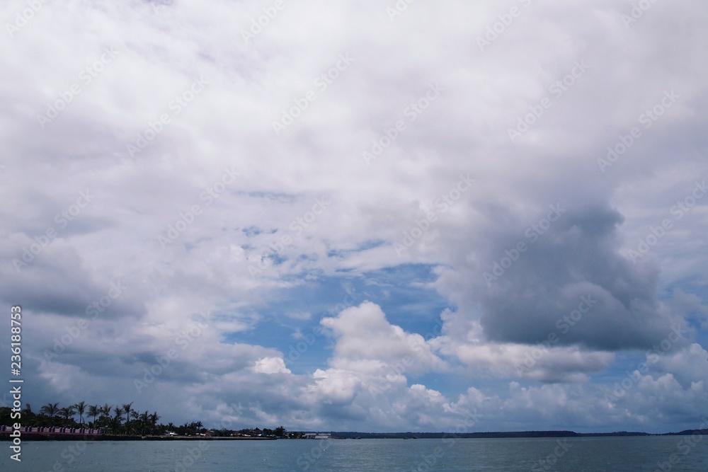 Beautiful panoramic view of wide open sky with huge cumulus white clouds on cloudy day over the sea with coastal feature and pier in distant view in Masinloc, Zambales, Philippines Beautiful panoramic view of wide open sky with huge cumulus white clouds on cloudy day over the sea with coastal feature and pier in distant view in Masinloc, Zambales, Philippines