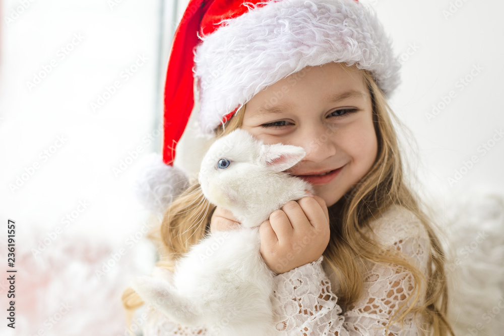 Obraz premium little girl in white dress with a little girl in red dress sitting by the window waiting for Christmas and Santa Claus