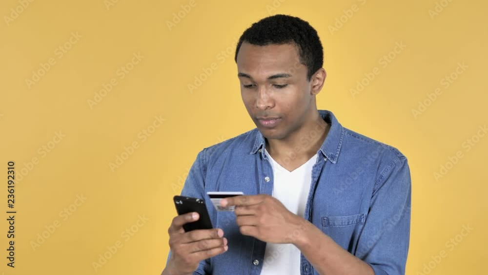 Online Shopping on Smartphone by Young African Man Isolated on Yellow Background Online Shopping on Smartphone by Young African Man Isolated on Yellow Background