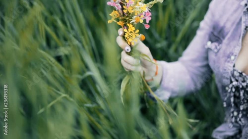 Slavic girl making a wreath. Flowers in the field. Girl in the field. Pagan Slavic rite. Pagan rite. Slavic girl making a wreath. Paganism. Woman making a wreath. Girl sorting the wildflowers photo