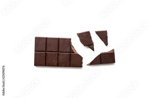 Broken dark chocolate bar isolated on white table. Horizontal composition. Top view