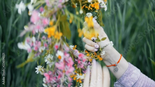 Flowers in the field. Girl in the field. Pagan Slavic rite. Pagan rite. Paganism. Girl making a wreath. Girl sorting the wildflowers. Girl binding the flowers.