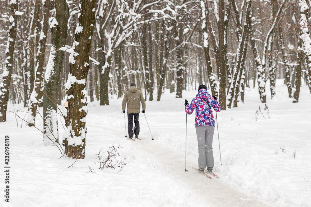 Couple of people enjoying cross-country skiing in city park or forest in winter. Family Sport outdoor activities in winter season concept. Healthy lifestyle