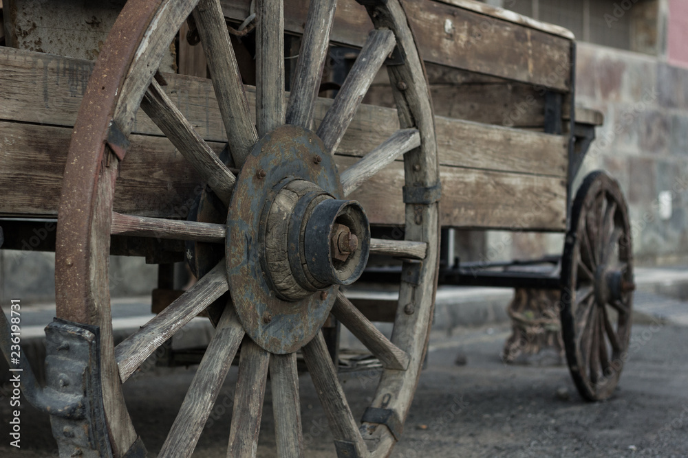 Rusty metal wheel of old wooden cart. Abandoned horse wagon, traditional western films transportation
