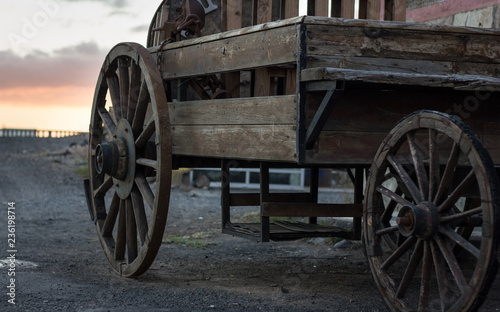 Wooden coach with sunset sky on background. Rusty old western carriage, vintage transportation concept