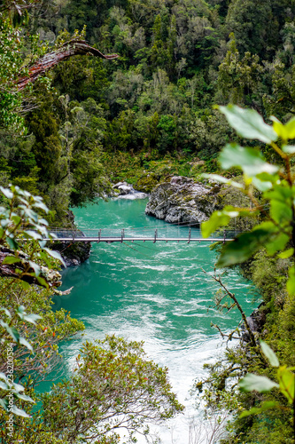 A swing bridge crosses bright turquoise waters and white rocks at Hokitika Gorge on the west coast of New Zealand s South Island 