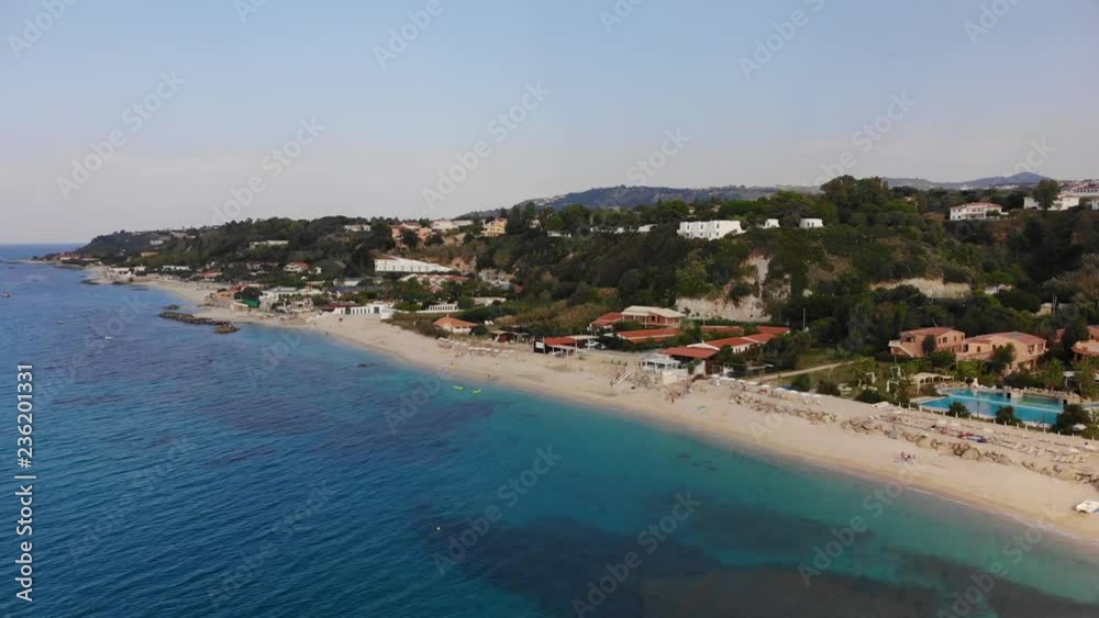 Sandy beach with hotels and resorts. Aerial view of azure sea and hilly coastline of Italy Sandy beach with hotels and resorts. Aerial view of azure sea and hilly coastline of Italy