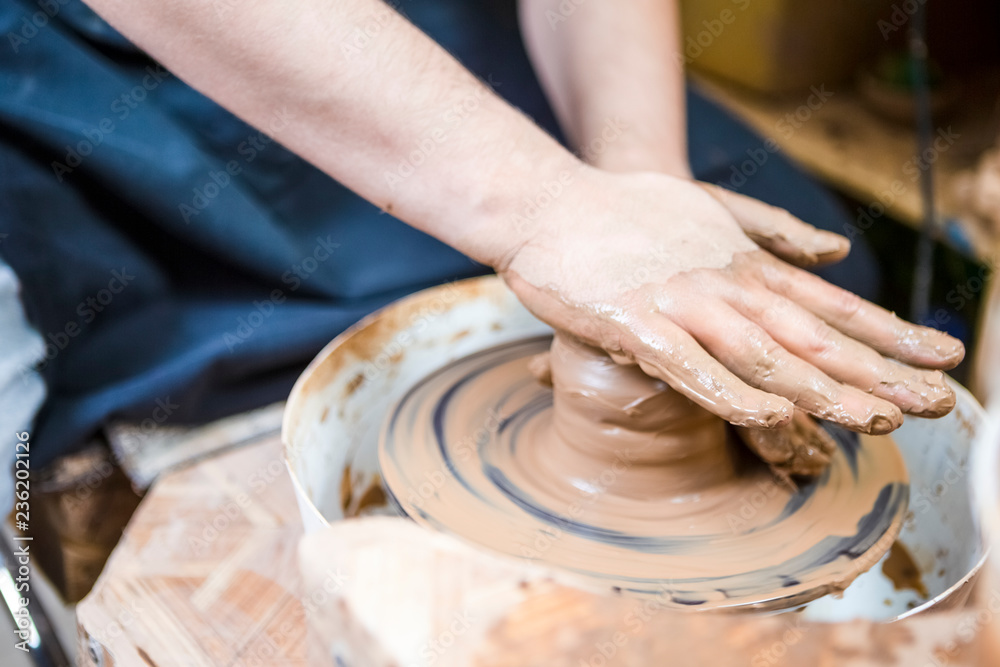 Professions Ideas. Closeup of Male Hands Working with Lump of Clay on Potter's Wheel in Workshop. Pressing it for Getting Form and Shape. Professions Ideas. Closeup of Male Hands Working with Lump of Clay on Potter's Wheel in Workshop. Pressing it for Getting Form and Shape.