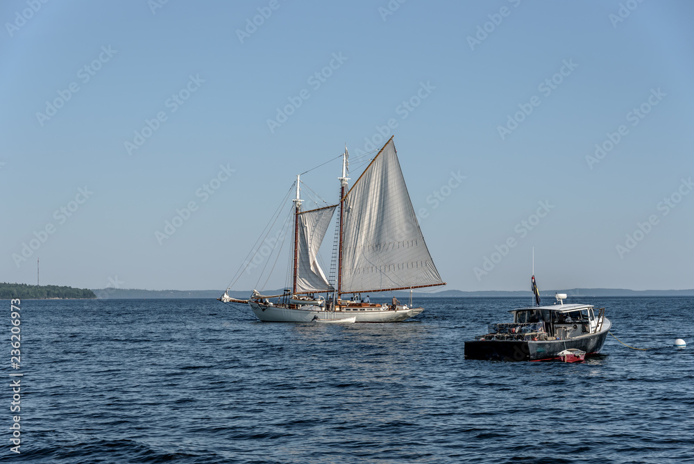 A Maine Lobster Boat Anchored Next to a Sailboat in a Bay in New England 