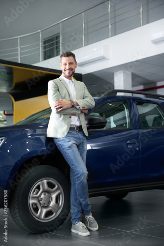 Man near new car in modern auto dealership