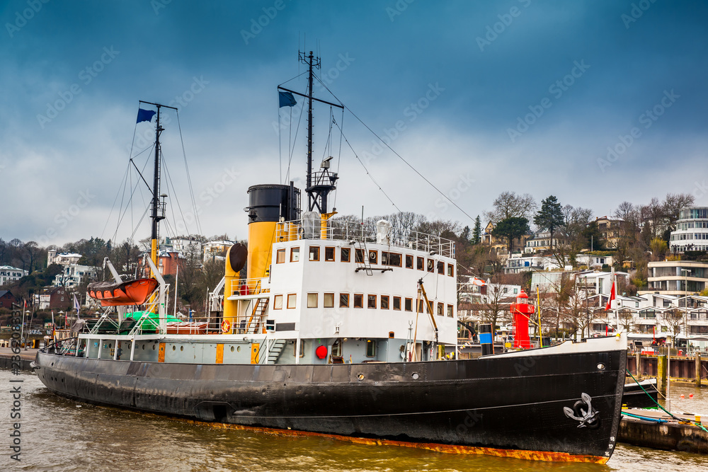 Naklejka premium Ship and buildings on the banks of the Elbe River in Hamburg in a cold end of winter day