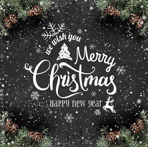 Christmas and New Year Typographical on dark holiday background with frame of Fir branches, pine cones, snowflakes. Xmas and Happy New Year theme, snow. Flat lay, top view