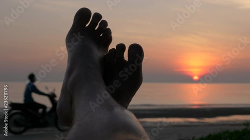 Relaxing at beach - Foot against sunset when motorbike drives by