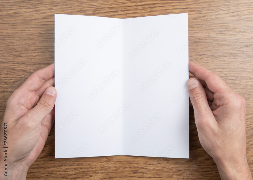 Mens hands holding white booklet Mens hands holding white booklet