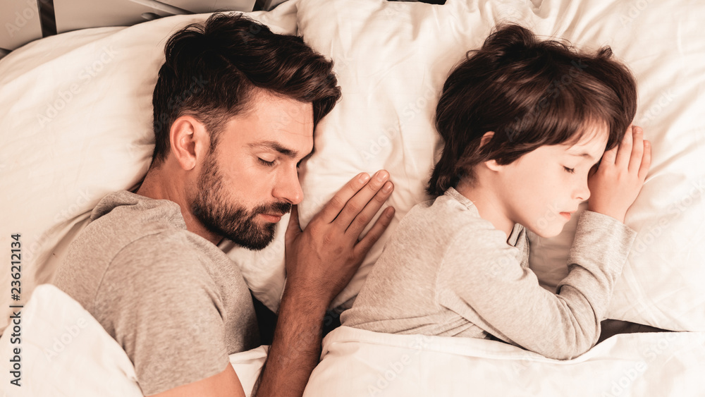 Little Son with Tired Sleeping Father in Bed. Little Son with Tired Sleeping Father in Bed.