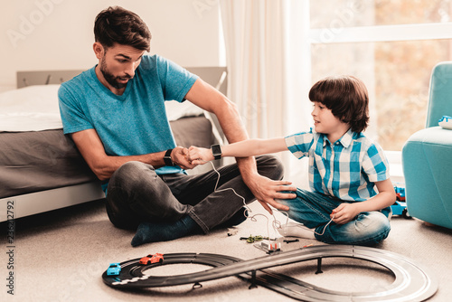 Bearded Father and Son Playing with Toy Race Road. © VadimGuzhva