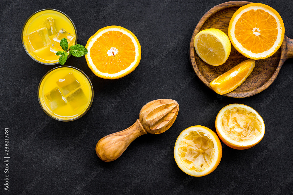 Squeeze fresh oranges with juicer. Orange juice in glass near half cut oranges on black background top view Squeeze fresh oranges with juicer. Orange juice in glass near half cut oranges on black background top view