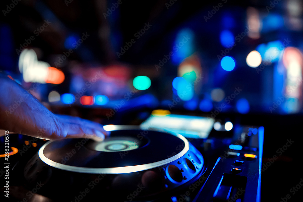 Obraz premium Dj playing the track in the nightclub at a party. In the background laser light show