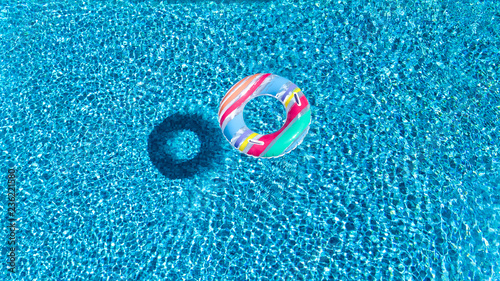 Aerial view of colorful inflatable ring donut toy in swimming pool water from above, family vacation concept background 