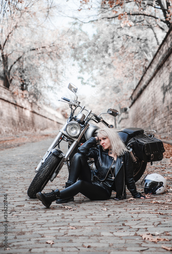 Fototapeta premium Beautiful biker woman posing outdoor with motorcycle. 