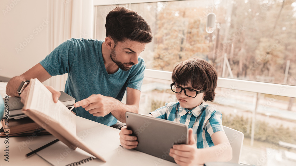 Father Trying to Help Son in Glasses with Homework
