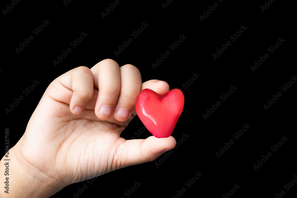 Isolated Hand holding a red candy shape heart on a black background. Isolated Hand holding a red candy shape heart on a black background.