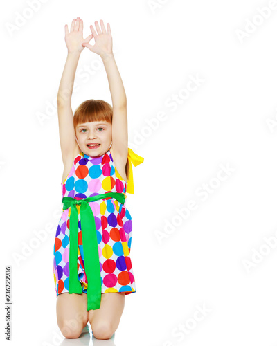 A little girl in a dress with a pattern from multi-colored circl