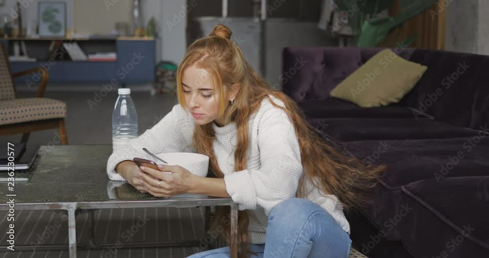 Woman using her phone while having breakfast Woman using her phone while having breakfast