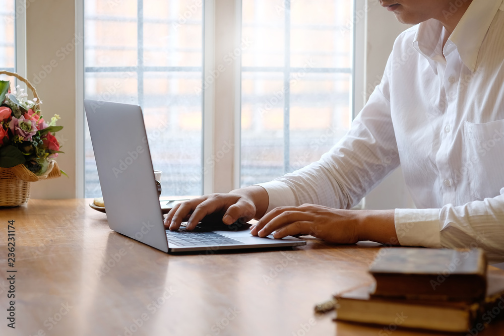 Cropped Man using laptop computer and books with coffee on office desk. Cropped Man using laptop computer and books with coffee on office desk.