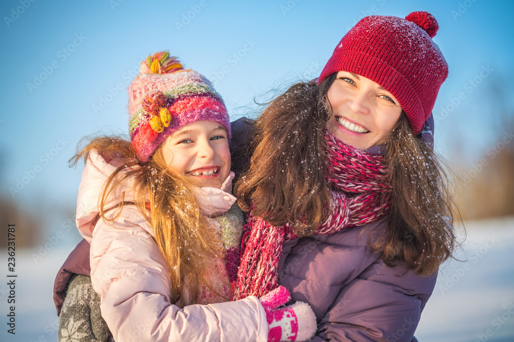 Fototapeta premium Little girl and her mother playing outdoors at sunny winter day